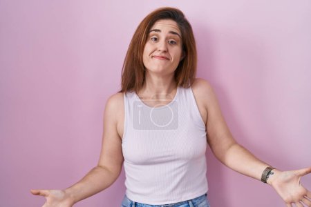 Photo for Brunette woman standing over pink background smiling cheerful with open arms as friendly welcome, positive and confident greetings - Royalty Free Image