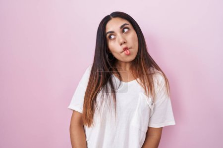 Téléchargez les photos : Jeune femme arabe debout sur fond rose faisant visage de poisson avec des lèvres, geste fou et comique. expression drôle. - en image libre de droit