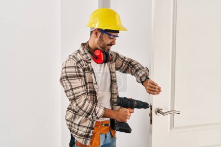 Photo for Young hispanic man worker smiling confident repairing door at home - Royalty Free Image