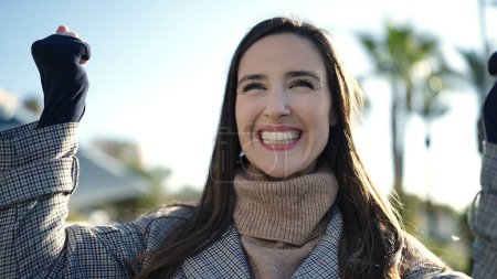 Téléchargez les photos : Belle femme hispanique souriant confiance debout avec expression gagnante à la rue - en image libre de droit
