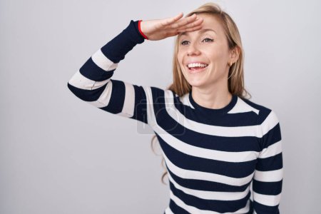 Photo for Young caucasian woman wearing casual navy sweater very happy and smiling looking far away with hand over head. searching concept. - Royalty Free Image