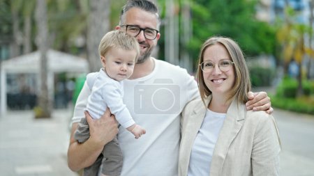 Photo for Family of mother, father and baby smiling together looking a the camera at street - Royalty Free Image
