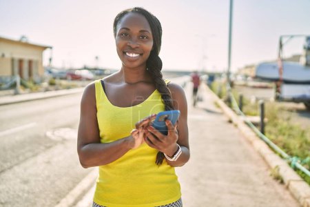 Photo for African american woman wearing sportswear using smartphone at street - Royalty Free Image