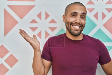 Téléchargez les photos : Homme hispanique avec barbe debout sur un mur coloré célébrant la réalisation avec sourire heureux et expression gagnante avec la main levée - en image libre de droit