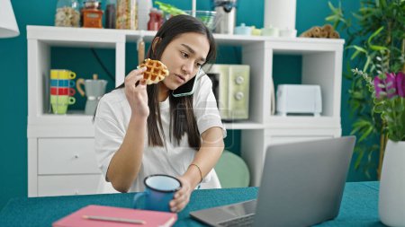 Téléchargez les photos : Jeune belle femme hispanique petit déjeuner parlant sur smartphone à la salle à manger - en image libre de droit
