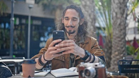 Photo for Young hispanic man tourist using smartphone sitting on table at coffee shop terrace - Royalty Free Image