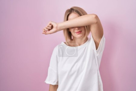 Photo for Young caucasian woman standing over pink background covering eyes with arm, looking serious and sad. sightless, hiding and rejection concept - Royalty Free Image