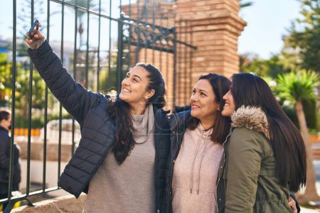 Foto de Three woman mother and daughters make selfie by the smartphone at street - Imagen libre de derechos