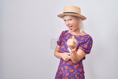 Photo for Young caucasian woman wearing flowers dress and summer hat beckoning come here gesture with hand inviting welcoming happy and smiling - Royalty Free Image