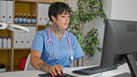 Téléchargez les photos : Femme hispanique avec amputé bras médecin en utilisant l'ordinateur de travail à la clinique - en image libre de droit