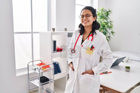 Téléchargez les photos : Jeune femme latine portant l'uniforme de médecin debout à la clinique - en image libre de droit