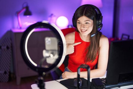 Photo for Young caucasian woman playing video games recording with smartphone pointing finger to one self smiling happy and proud - Royalty Free Image