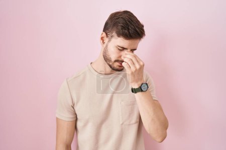 Foto de Hispanic man with beard standing over pink background tired rubbing nose and eyes feeling fatigue and headache. stress and frustration concept. - Imagen libre de derechos