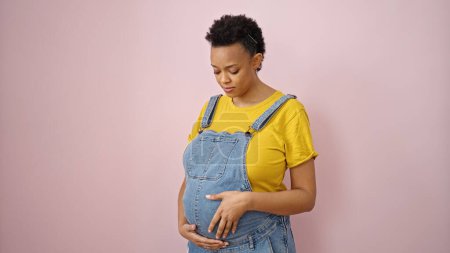 Photo for Young pregnant woman touching belly over isolated pink background - Royalty Free Image