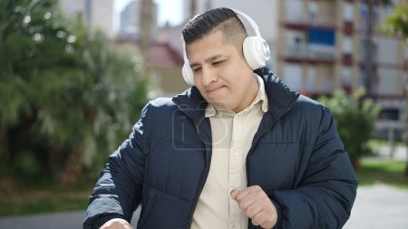 Foto de Young hispanic man listening to music and dancing at park - Imagen libre de derechos