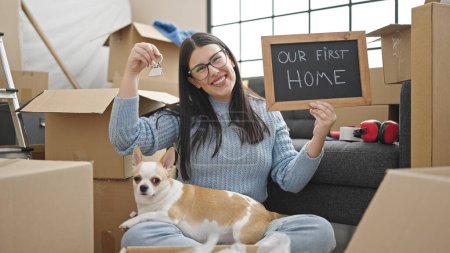 Photo for Young hispanic woman with chihuahua dog smiling confident holding blackboard and keys at new home - Royalty Free Image