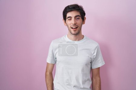 Téléchargez les photos : Young hispanic man standing over pink background winking looking at the camera with sexy expression, cheerful and happy face. - en image libre de droit