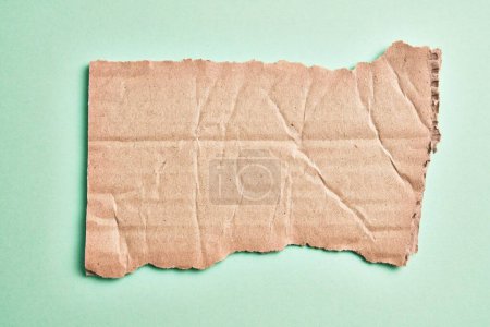Téléchargez les photos : Un morceau de carton déchiré sur fond vert isolé - en image libre de droit