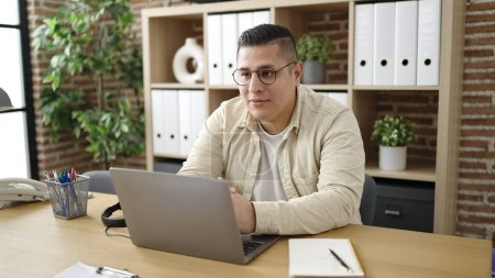 Téléchargez les photos : Young hispanic man business worker using laptop at office - en image libre de droit