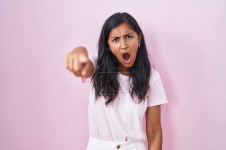 Photo for Young hispanic woman standing over pink background pointing displeased and frustrated to the camera, angry and furious with you - Royalty Free Image