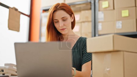 Téléchargez les photos : Jeune rousse femme commerce électronique travailleur d'affaires en utilisant un ordinateur portable au bureau - en image libre de droit