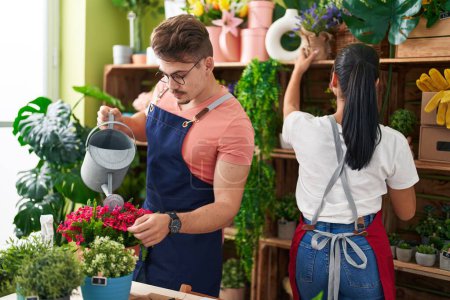 Téléchargez les photos : Fleuristes homme et femme arrosage usine travaillant à la boutique de fleurs - en image libre de droit