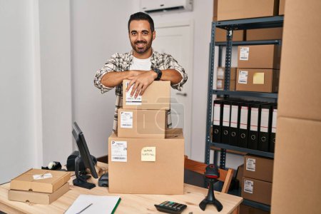 Téléchargez les photos : Jeune homme hispanique ecommerce travailleur d'affaires s'appuyant sur des paquets au bureau - en image libre de droit