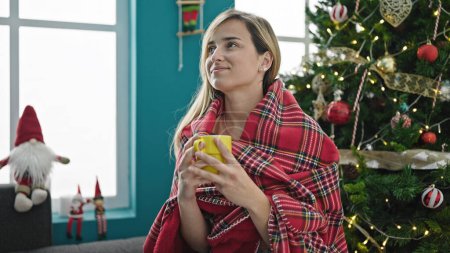 Photo for Young blonde woman smelling cup of coffee celebrating christmas at home - Royalty Free Image