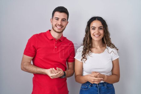 Téléchargez les photos : Jeune couple hispanique debout sur fond isolé avec les mains jointes et les doigts croisés souriant détendu et joyeux. succès et optimisme - en image libre de droit