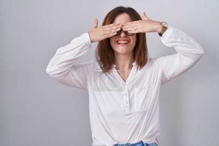 Photo for Brunette woman standing over white isolated background covering eyes with hands smiling cheerful and funny. blind concept. - Royalty Free Image