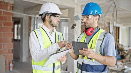 Téléchargez les photos : Deux hommes constructeurs et architecte en utilisant touchpad serrent la main sur le chantier de construction - en image libre de droit