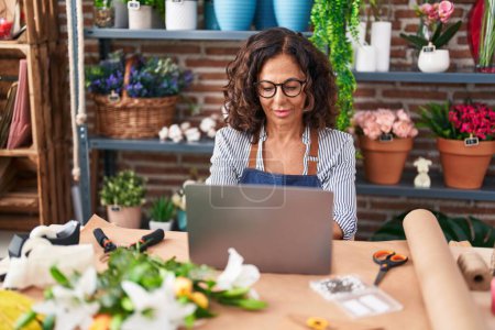 Photo for Middle age woman florist smiling confident using laptop at flower shop - Royalty Free Image