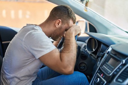 Téléchargez les photos : Young caucasian man stressed driving car at street - en image libre de droit