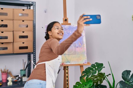 Foto de Joven mujer afroamericana artista sonriendo confiado haciendo selfie por el teléfono inteligente en el estudio de arte - Imagen libre de derechos