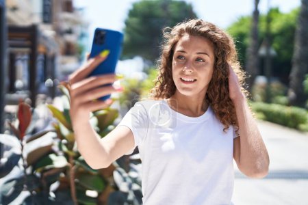 Foto de Joven hermosa mujer hispana sonriendo confiada haciendo selfie por el teléfono inteligente en el parque - Imagen libre de derechos