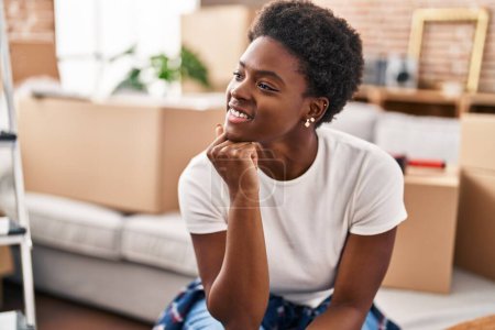 Téléchargez les photos : Femme afro-américaine souriante confiante assise sur le canapé à la nouvelle maison - en image libre de droit