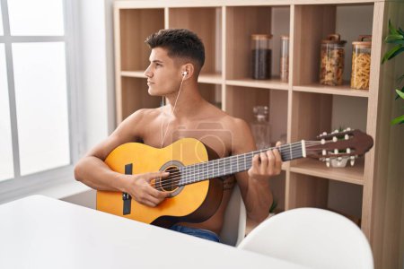 Photo for Young hispanic man playing classical guitar at home - Royalty Free Image