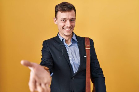 Téléchargez les photos : Homme d'affaires caucasien sur fond jaune souriant joyeuse offrant main de paume donnant assistance et acceptation. - en image libre de droit
