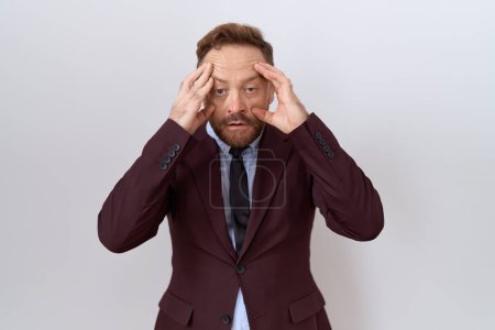 Téléchargez les photos : Middle age business man with beard wearing suit and tie trying to open eyes with fingers, sleepy and tired for morning fatigue - en image libre de droit