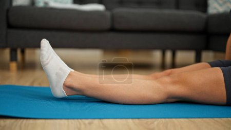 Photo for Young beautiful hispanic woman stretching legs sitting on floor at home - Royalty Free Image