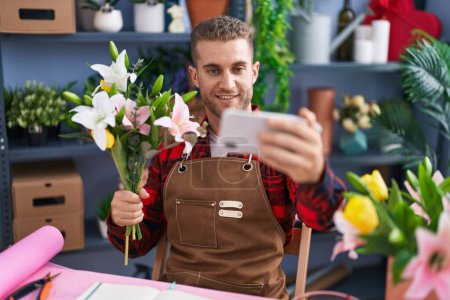 Photo for Young caucasian man florist make selfie by smartphone holding bouquet of flowers at flower shop - Royalty Free Image