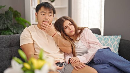 Photo for Man and woman couple watching tv with serious expression at home - Royalty Free Image