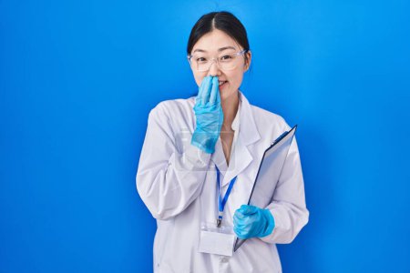 Photo for Chinese young woman working at scientist laboratory laughing and embarrassed giggle covering mouth with hands, gossip and scandal concept - Royalty Free Image