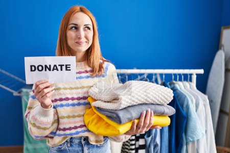 Foto de Young woman holding donations for charity smiling looking to the side and staring away thinking. - Imagen libre de derechos