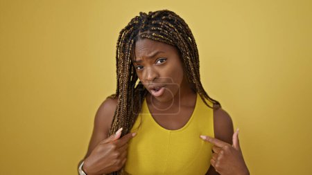 Téléchargez les photos : Femme afro-américaine se montrant avec une expression surprise sur fond jaune isolé - en image libre de droit