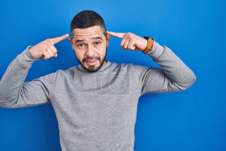 Téléchargez les photos : Hispanic man standing over blue background smiling pointing to head with both hands finger, great idea or thought, good memory - en image libre de droit