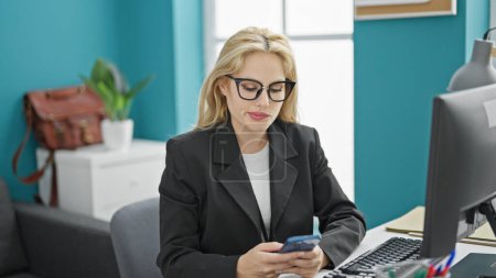 Foto de Mujer joven rubia trabajadora de negocios usando smartphone trabajando en la oficina - Imagen libre de derechos