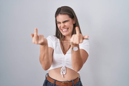 Foto de Young beautiful woman wearing casual white t shirt showing middle finger doing fuck you bad expression, provocation and rude attitude. screaming excited - Imagen libre de derechos