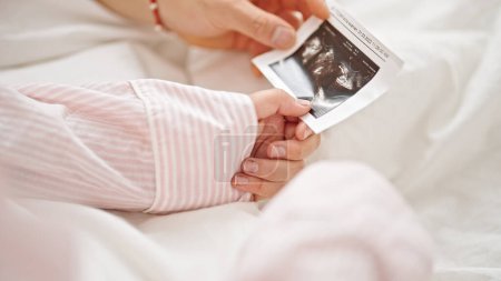 Téléchargez les photos : Homme et femme couple tenant échographie bébé photo dans la chambre - en image libre de droit