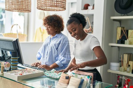 Téléchargez les photos : Africaines américaines assistantes de magasin souriantes confiantes travaillant dans un magasin de vêtements - en image libre de droit
